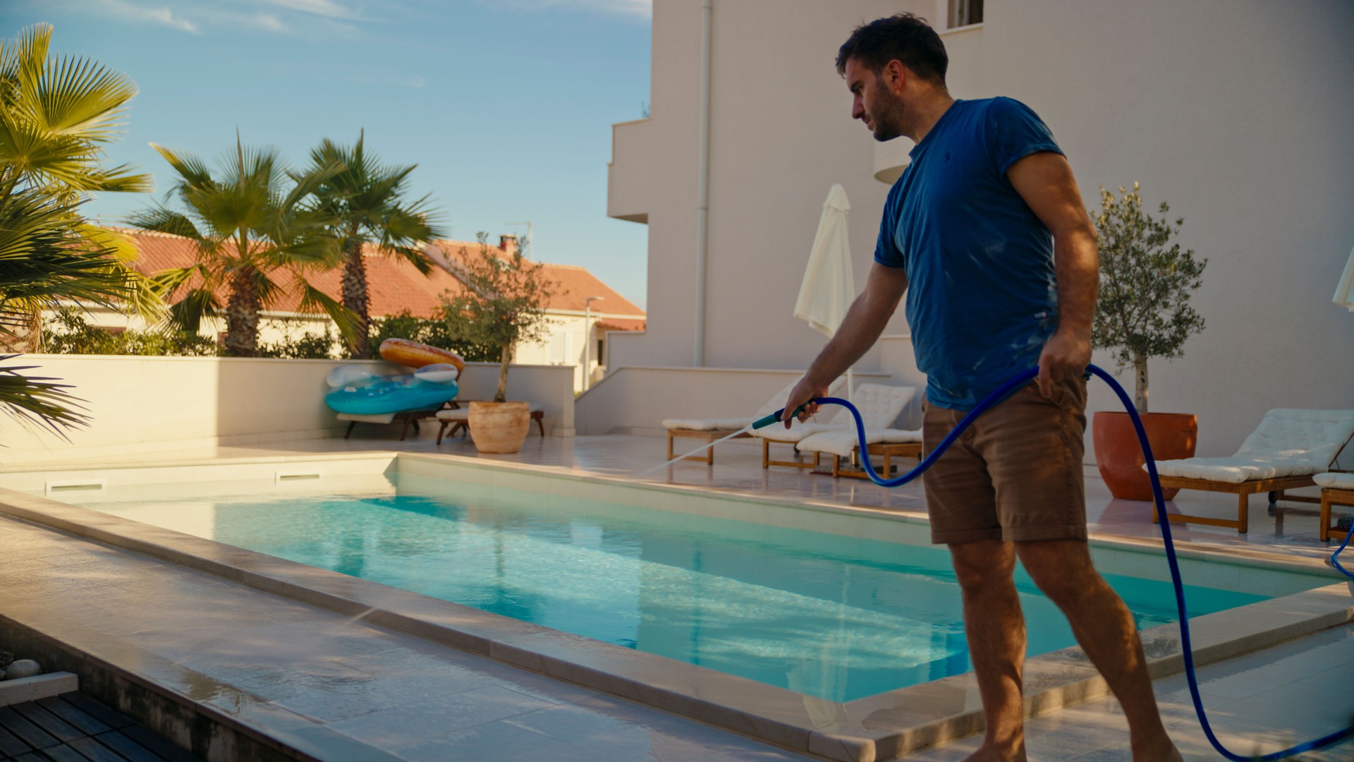 Mid Adult Caucasian Male Cleaning Pool with Hose